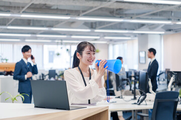 オフィスでメガホンを使って話す若い女性