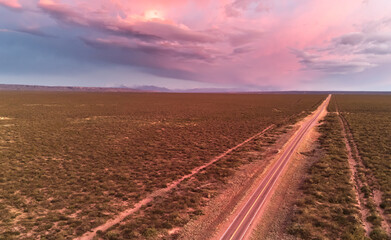 Asphalt road across the desert at dawn. Aerial view.