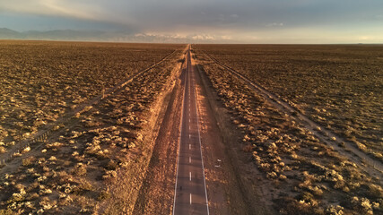 Asphalt road across the desert at sunrise. Aerial view.