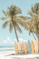 A photo of pastel-colored surfboards leaning against palm trees on the beach, with soft tones