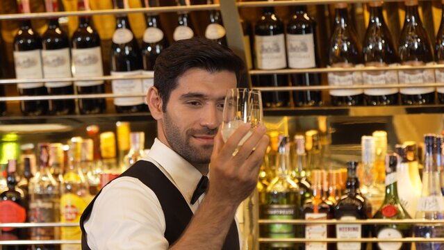Good looking bartender chilling glass with ice for serving customer at beverage bar counter of welcome drink with charm professionalism, making great first impression warm smiling greeting. Vinosity.