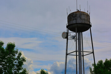 Old industrial water tower with antennas under cloudy sky, Québec, Canada