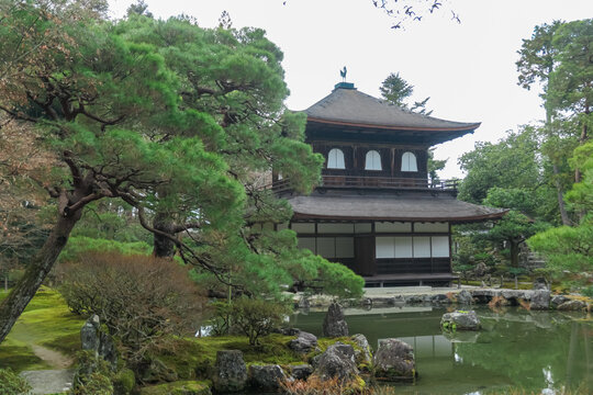 The iconic Ginkaku-ji Temple, the Silver Pavilion, stands serenely over its reflecting pond, surrounded by a meticulously manicured Japanese garden and ancient pine trees in historic Kyoto, Japan.