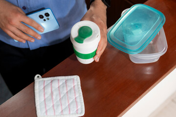 High angle view of someone taking a green and white portable cup with coffee and smartphone. The...