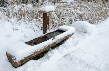A wooden bench with a metal post is covered in snow