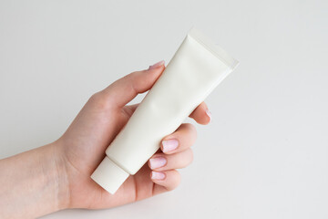 Minimalist hand holding cosmetic cream tube