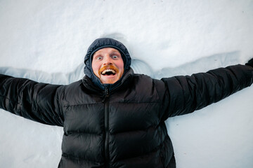 A man is laying in the snow with his arms outstretched