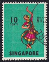 A girl dances in national clothes on a 1973 Singapore postage stamp. Traditional Dances and Musical Instruments Series.
