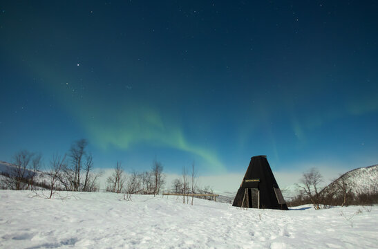traditional tipi over the mountains and northern lights in norway
