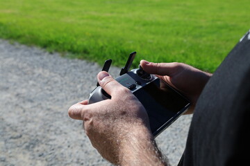 Calw, Germany. May 11, 2025. Close-up of hands holding a remote control for a drone, outdoor...