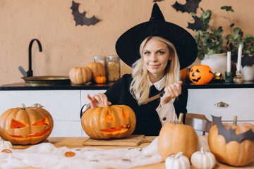 Young woman carving Halloween pumpkins wearing witch costume