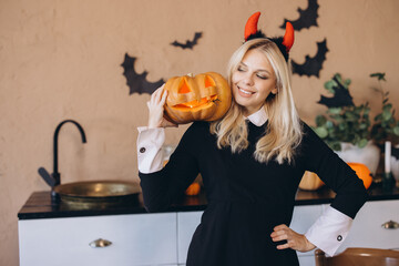 Smiling woman wearing Halloween costume holding jack o' lantern