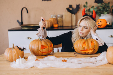 Woman Carving Halloween Pumpkins at Home Wearing Devil Horns