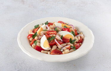 Protein salad Piyaz with eggs, white beans, tomatoes, greens on a white background. Turkish food.