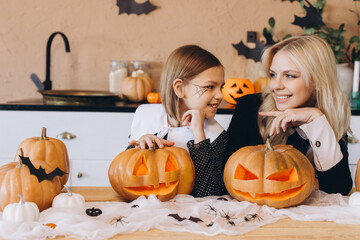 Mother and daughter carving pumpkins for Halloween party