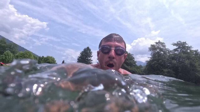 Time lapse tourist dives in the lake of Levico, in Trentino, in northern Italy, and takes a swim. The man is forty years old and is of Caucasian origin