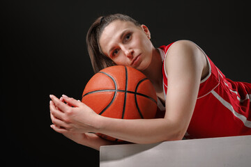 Female Basketball Player Resting with Ball after Game on Dark Background, Professional Sports...