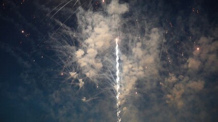 Fireworks exploding creating smoke and light trails in the night sky