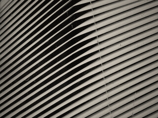 white colored matallic window shades in a window during night slightly damaged by a bend