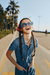 Lifestyle woman in modern boho-western denim street style laughing joyfully outdoors with film color effect, braided hair, oversized sunglasses, and casual summer vibe.