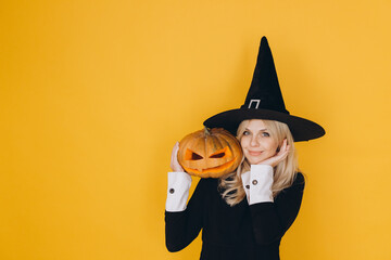 Woman wearing witch costume holding jack o' lantern for Halloween party