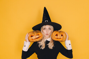 Magician holding two jack o' lanterns with funny faces on yellow background