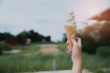 Melting ice cream. Person Holding Cone of Soft Serve Ice Cream Against Nature Background in Warm...