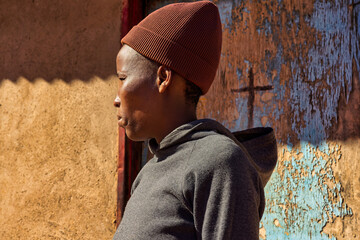 africa village, african smiling single woman, in front of the house in the yard, profile view, wall...