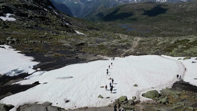 Hikers Walking on Snow Trail to Trolltunga Norway, aerial view from a drone