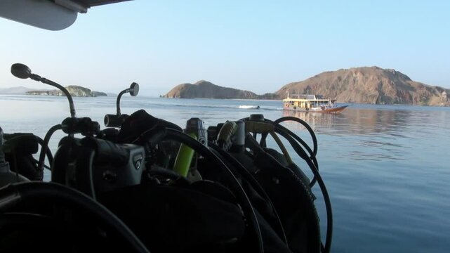 Scuba diving gear awaits on the boat as it cruises near small islands. The calm waters of Bali, Indonesia, beckon for an underwater exploration at dawn.