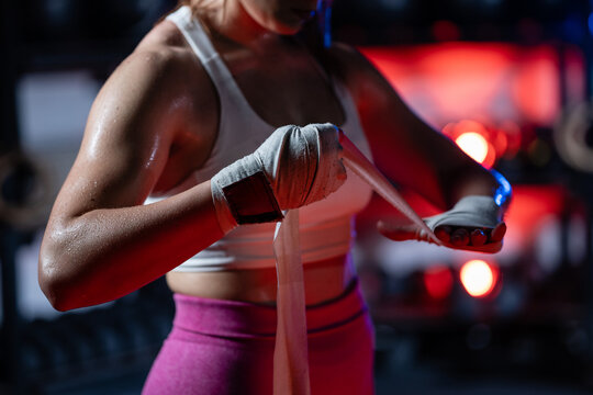 Female boxer wrapping hands getting ready for training in boxing club