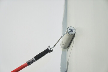 Roller painting of the wall, working painting on the surface, painting the walls in the apartment, repair with white paint. With space to copy. High quality photo