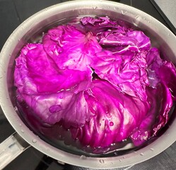 vibrant purple cabbage in a shiny stainless steel pot submerged in water