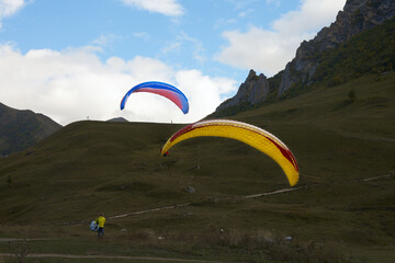 Mountain Aeroclub. Paragliders landing against the backdrop of picturesque rocky mountains.