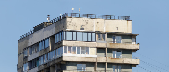 Close-up of the upper floors of a Soviet-style apartment building, showing aging balconies, rooftop...