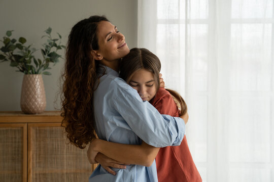 Young loving mother hugging her teenage daughter, mom demonstrating unconditional love for child, mommy cuddling supporting upset teen girl while spending time together at home. Mother-daughter bond  - Powered by Adobe