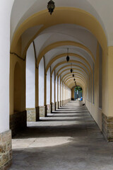 Long shaded passageway with repeating arches and hanging lanterns in Saint Petersburg, creating a rhythmic pattern of light and shadow.