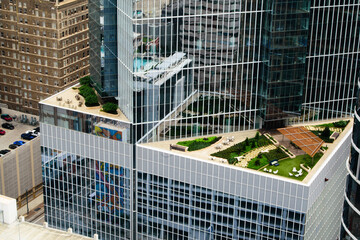 Modern glass skyscraper with rooftop gardens, outdoor seating, and green terraces. Aerial view...