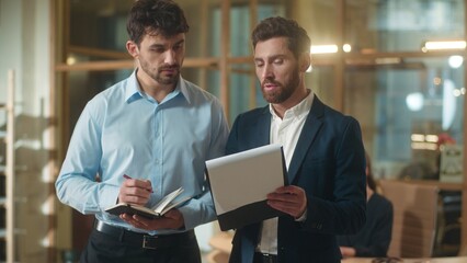 Professional businessmen adults Caucasian men co-workers partners discuss corporate documents...