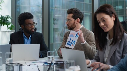 Caucasian businessman talking to business group pointing graph chart employees financial presentation multiracial workers men women listen team leader at conference table in office meeting briefing