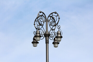 An intricately designed vintage street lamp with five glass lanterns and decorative metalwork...