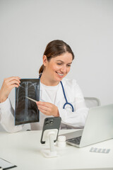Telemedicine. Caucasian female doctor communicates with patient on laptop and shows x-ray of lungs. 