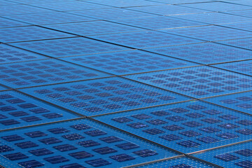 A sprawling grid of blue photovoltaic solar panels, arranged in precise geometric alignment,...