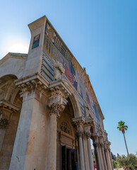 Obraz premium The Church of All Nations in Jerusalem, with its mosaic facade, stands against a clear blue sky.