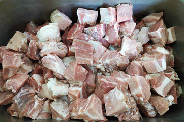pieces of fresh pork meat are cut and placed in an iron container. preparation for marinating and...