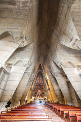 A wide-angle view of the interior of the Basilica of Our Lady of Altagracia in Higüey, Dominican Republic. The photograph captures the soaring concrete arches, stained glass windows.