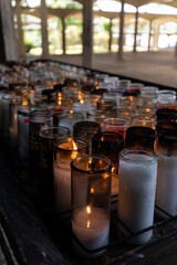 DescriptionRows of lit votive candles glowing softly in a peaceful sanctuary, symbolizing hope, remembrance, and silent prayers. Captured indoors using natural light.