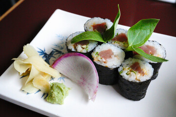 Spicy salmon sushi 6 rolls in white plate with ginger and wasabi on the side          