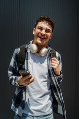Portrait of a young adult man student smile with wireless headphones on black wall background
