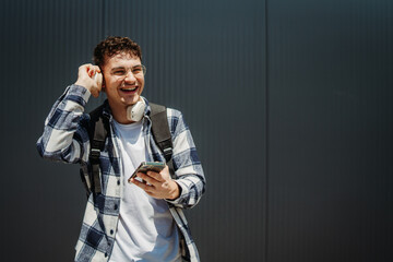 Portrait of a young adult man student smile with wireless headphones on black wall background